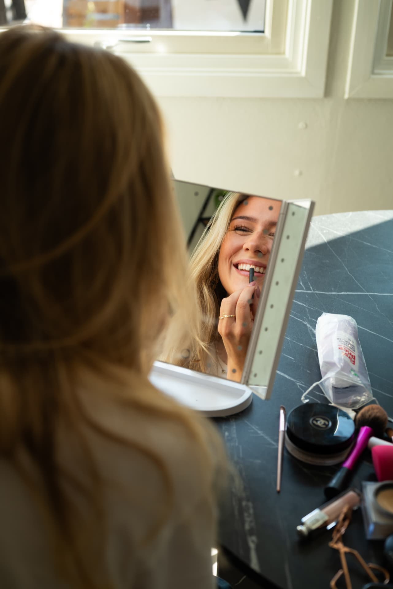 Vilde smiler mens hun sminker seg foran speilet