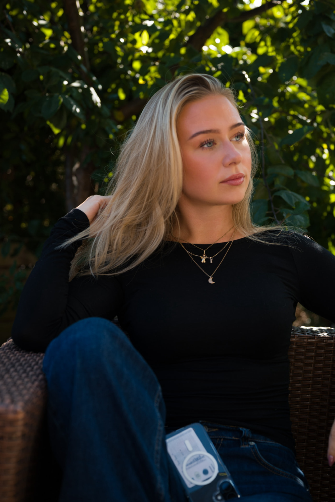 Vilde sitter ute i solen med grønne omgivelser bak
