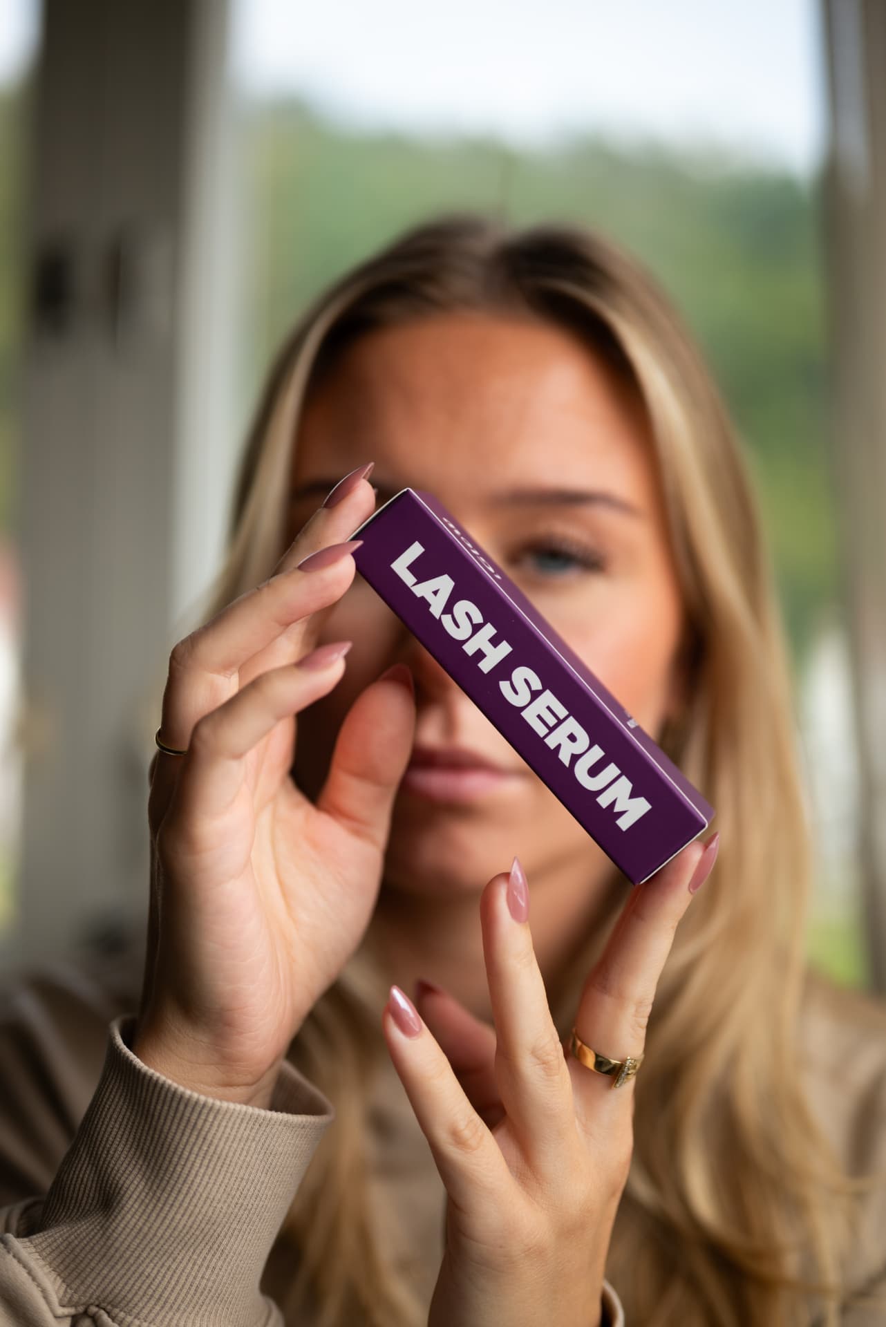 Nærbilde av Iglow lash serum-esken foran Vildes øye